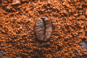 Single coffee bean on top of finely ground coffee